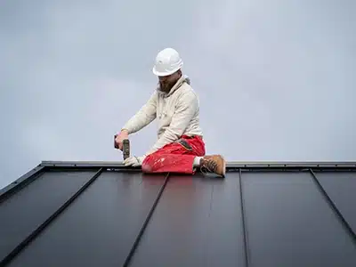 Trabajador instalando caballete en techo metálico negro.