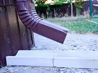 Bajada de agua marrón conectada desde canaleta hacia el suelo